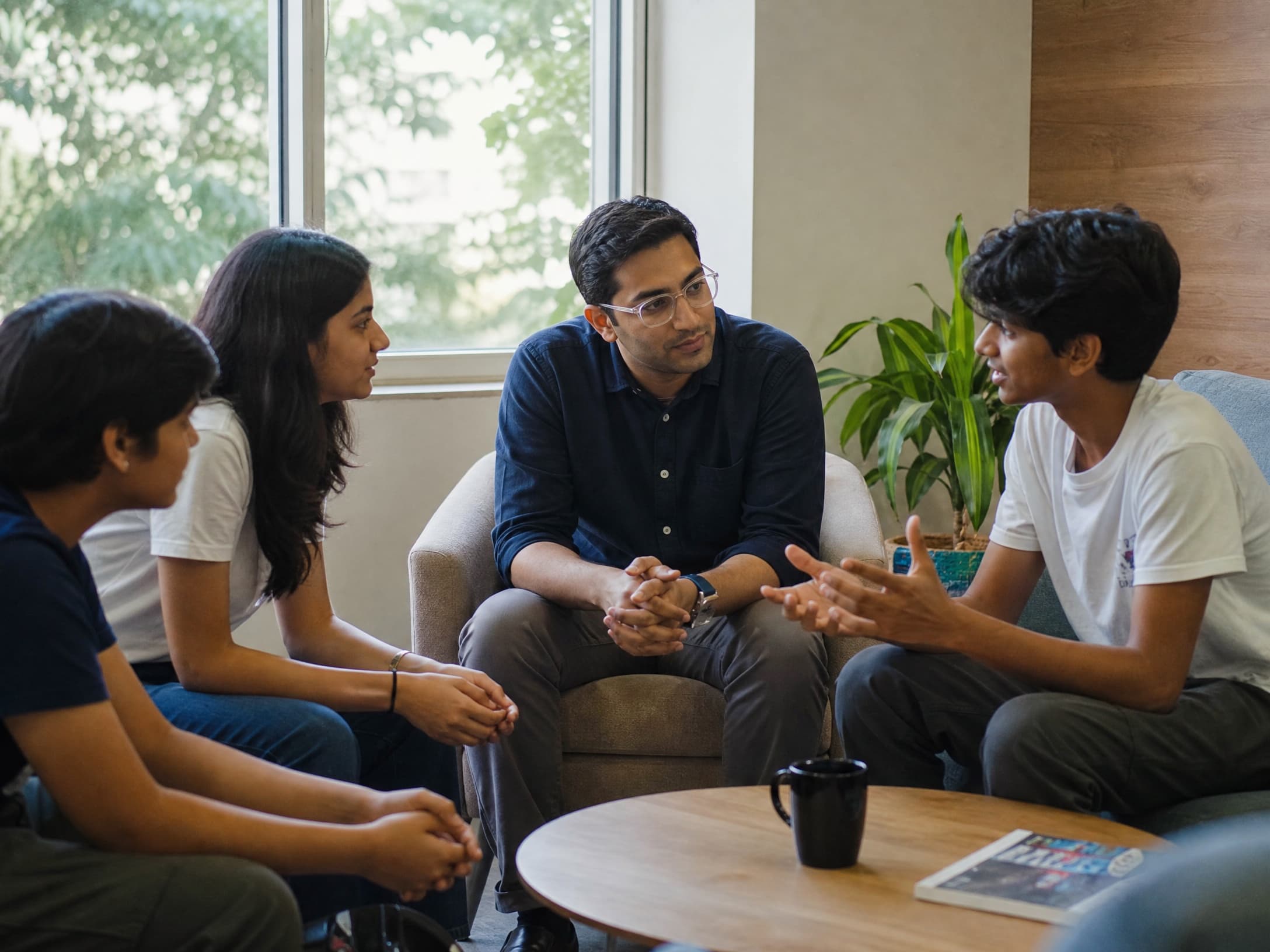 A mentor listening attentively to a small group of teenagers