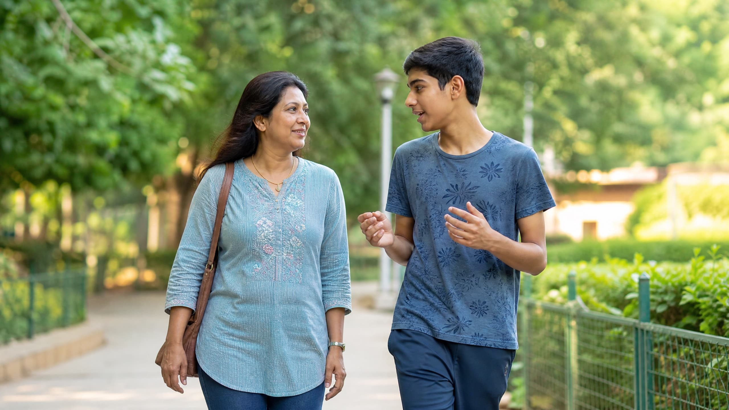 An Indian parent and teenager walking and talking together outdoors